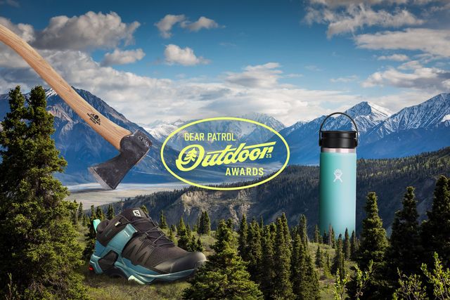an axe, water bottle, and hiking shoe in a mountainous landscape